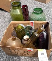 Box of assorted glass vases and bottles on pavement