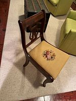 Front angled view of lyre-back chair showing seat upholstery and leg design