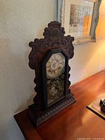Angled left view of carved mahogany clock on desk