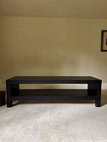 Front view of black TV stand showing overall shape and open shelf