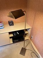 Full view of brass floor lamp next to cabinet, showing rectangular base, column and shade