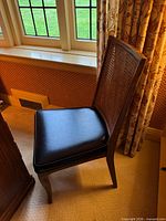 Side view of wooden chair showing full profile, leather seat, caned back