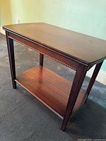 Three-quarter view of Dollcraft end table showing top, apron beading and shelf