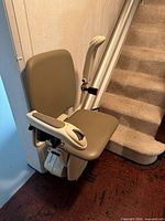 Stairlift chair folded at bottom of stairs on straight rail