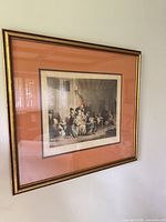 Framed print on wall showing full piece with gilt frame and salmon mat