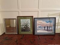 Overall view of three framed pieces: mirror, floral print, seascape print