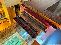 Stack of nine large books showing spines including National Geographic Atlas and others