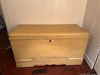 Front view of closed cedar chest showing painted exterior and scalloped base