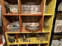 Shelving unit showing variety of glassware, plates, jars and planter