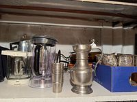 Shelf view with blender jar, pewter cups, pewter pitcher, goblets in box