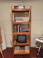 Front view of tall five-shelf solid wood bookcase with various items for scale