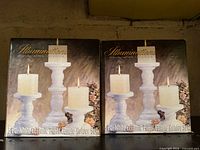 Front view of two boxed Illuminations 3-pc white ceramic candle holder sets