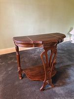 Three-quarter view showing overall table design, turned legs, carved support, lower shelf