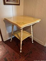 Full view of square painted table showing legs, shelf and top