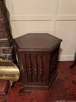 Front view of walnut hexagonal end table showing spindle door and brass handle