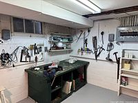 Overall view of workbench, pegboard, vise and wall-mounted tools
