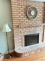 Floor lamp and wall clock on brick fireplace wall