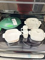 Group view showing green covered dish, two CorningWare casseroles with lids, open baking dish, salt and pepper shakers