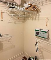 Closet corner showing boxed infrared heating pad on shelf and multiple hangers on wire racks