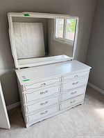 Front view of white dresser with eight drawers and mirror on top