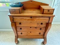 Front view of solid wood dresser showing four drawers, curved legs and top accessory boxes