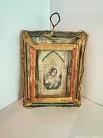 Front view shows saint image, cloth-trimmed frame and wire loop