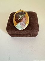 Front view of oval enamel cameo brooch on box