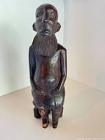 Full view of carved wood figurine showing seated form and overall finish