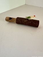 Side view of wooden whistle with ceramic bird on top