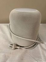 Front view of Apple HomePod with attached cable