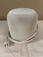 Front view of white Apple HomePod with attached power cable