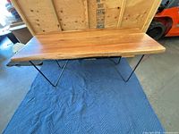 Full view of table on blue pad showing wood top and hairpin legs