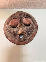 Front view of carved wooden Ghanaian mask with detailing
