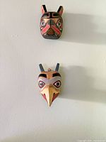 Both carved wooden masks mounted on wall