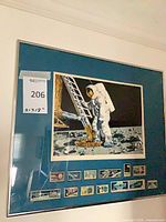Entire framed astronaut moon landing print with teal mat and small images along bottom