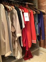 Mixed knit garments on hangers, beige ribbed cardigan, taupe sweater, red cardigan, blue items, purple belt visible