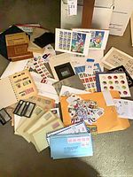 Overview of loose stamps, envelopes, album, booklets, catalog and accessories spread on floor