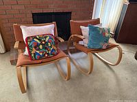Front view of both Plycraft bentwood rocking chairs with rust upholstery