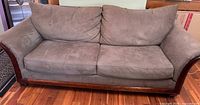 Front view of sofa showing three seat cushions, two back cushions and wood trim