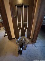 Pair of crutches leaning against door with walking boot on floor