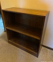 Front view of brown oak finish three-shelf bookcase
