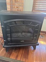 Front view of Duraflame electric fireplace stove showing arched glass door and black metal body