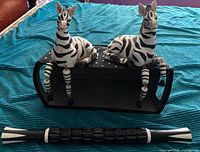 Two zebra figurines seated on polka-dot basket with ridged rod below