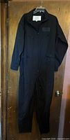 Full view of black flight suit hanging on door