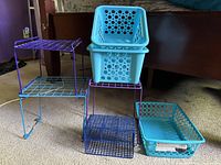 Front view showing all seven pieces: three wire shelf risers, two square turquoise bins, flat basket and wire mesh basket