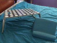 Lap desk set up with polka-dot top and teal cushion on bed