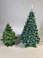Front view of both ceramic lighted Christmas trees showing size difference and cords