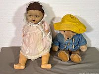 Front view of both items: composition doll and Paddington-style plush bear