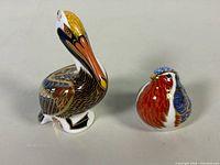 Brown Pelican and Robin paperweights side by side for scale comparison