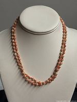 Full view of double-strand coral necklace on display bust